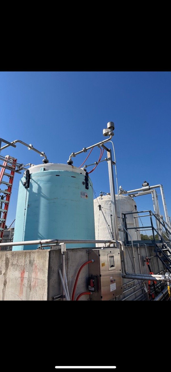 Blue 5,000-gallon HDPE double-wall storage tank shown outdoors with process piping; 1.9 specific gravity.